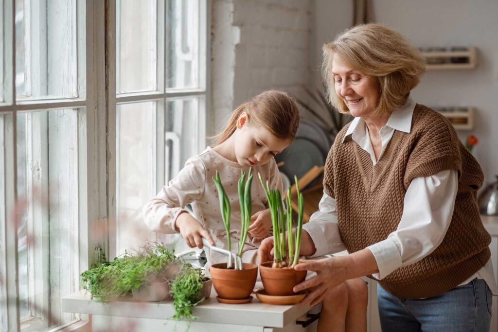 Junges Mädchen und ältere Frau pflanzen Pflanzen in Töpfe
