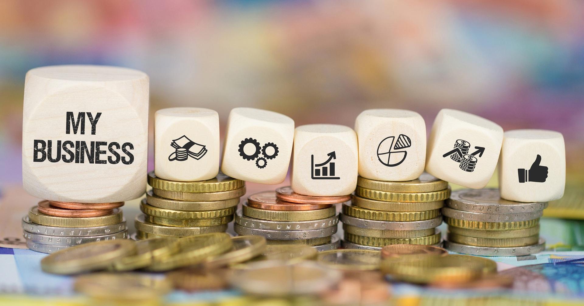 Geldmünzen und Würfel mit Symbolen für Wachstum und Erfolg | Kaltasphalt