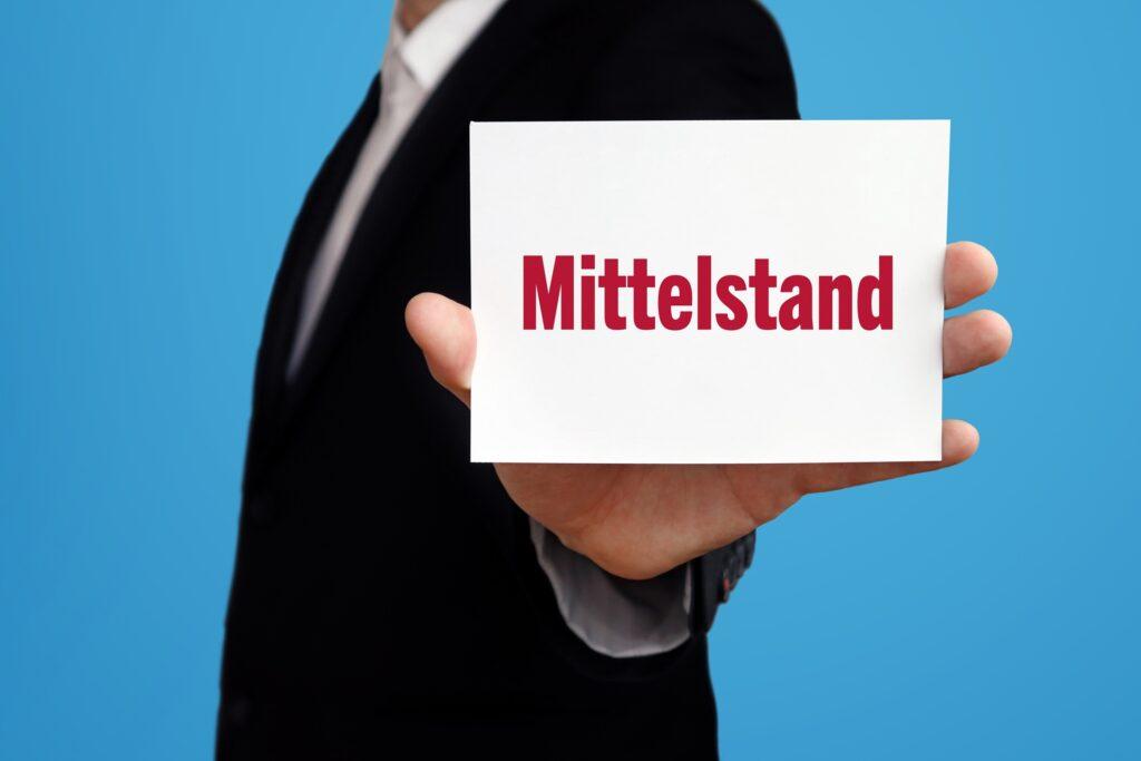 Geschäftsmann hält Schild mit dem Wort Mittelstand | Kaltasphalt